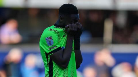 Ebou Adams covers his face after Pompey's loss at QPR