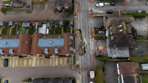 An aerial view of Godstone High Street showing the sinkholes. The street is cordoned off and houses line either side of the street.