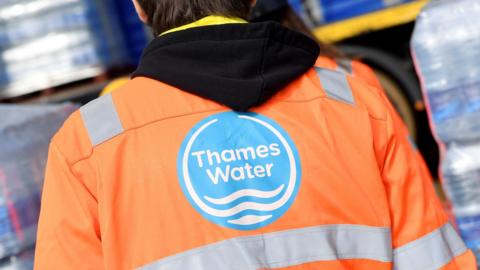 A Thames Water operative views pallets of bottled water for distribution