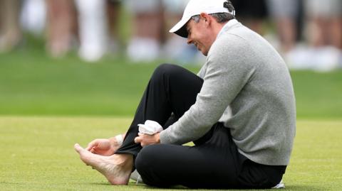 Rory McIlroy inspecting his injured toe while on the 18th fairway during Wednesday's practice round for the US PGA Championship