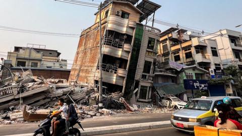 Commuters drive past a building that collapsed in the aftermath of a strong earthquake in Mandalay, Myanmar. March 30, 2025.
