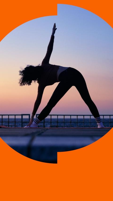 A silhouette of a woman doing yoga outside