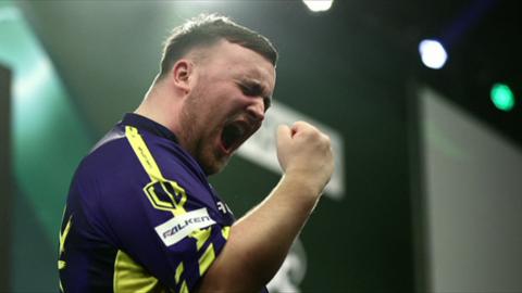 Darts player Luke Littler clenches his fist in victory whilst playing during the World Darts Championship.