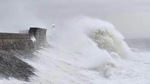A photo of large white waves hitting the coast on an overcast day.