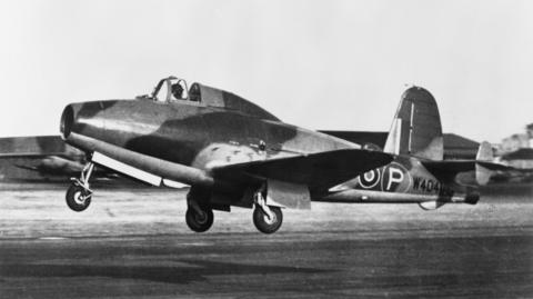 A black and white photo of an airplane taking off. The RAF circular logo is visible near its tail