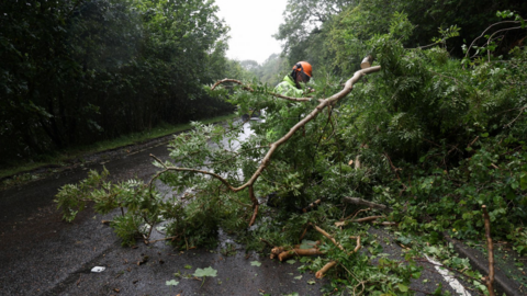 A worker removes a fallen tree blocking a part of the A82 road near Onich, as Storm Floris hits Scotland, 4 August, 2025.