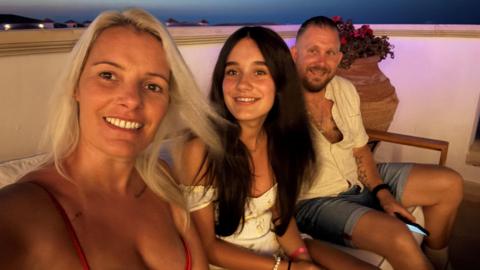 Marisa Noyce takes a selfie with her husband and daughter on a balcony on their holiday.
