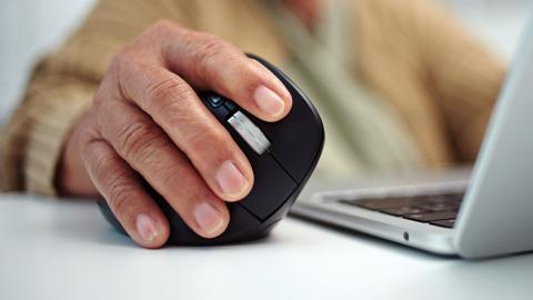Close-up hand of senior woman using a ergonomics mouse with a laptop.