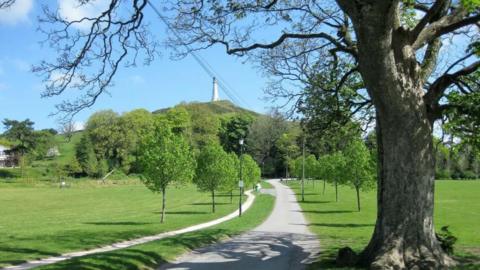 A general view of Ford Park. A path leads to a hill that then leads to the Sir John Barrow monument. The path is flanked by young trees and grass.