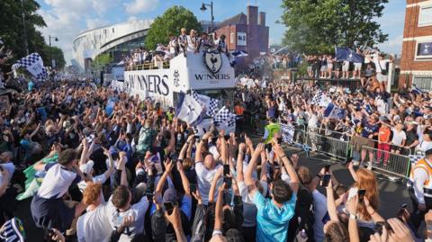 Fans take pictures as the Spurs bus passes the team's stadium 