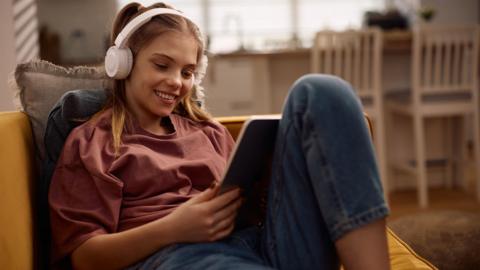 Happy girl with headphones surfing the net on digital tablet at home. - stock photo