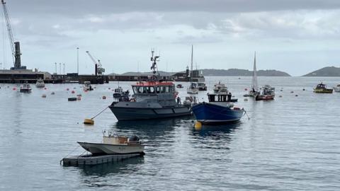 A boat called Leopardess in a harbour in Guernsey. It is surrounded by several other boats of various shapes and sizes.