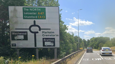 A roundabout sign on a sliproad of the A47 Soke Parkway. It is on a white background and has directions for Westwood (turn left), The NORTH, Leicester A47 and Stamford (A1) (straight on), and Marholm Cremator'm and Bretton (turn right)
