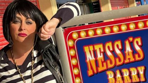 Nessa impersonator Kaz Barrett in full get up next to a sign for Nessa's Slots in Barry Island