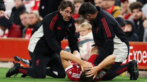 Giovanni Leoni on the pitch getting treatment from two physios.