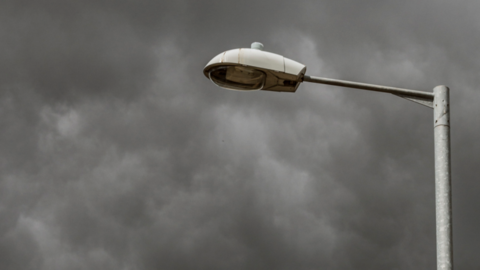 Close-up of a street light against a very cloudy sky.