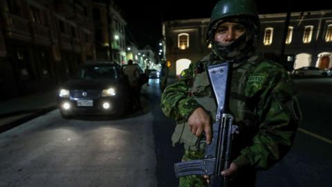 A soldier with a rifle patrols in Quito following the start of blackouts