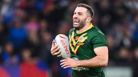 James Tedesco in an Australia jersey running from right to left with the ball, his mouth open to reveal a branded mouthguard