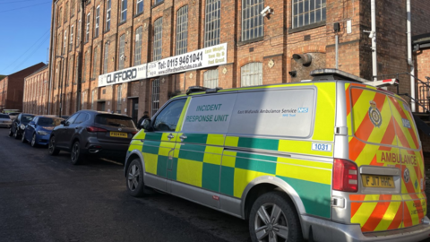 Ambulance on a road outside a Victorian-era former mill