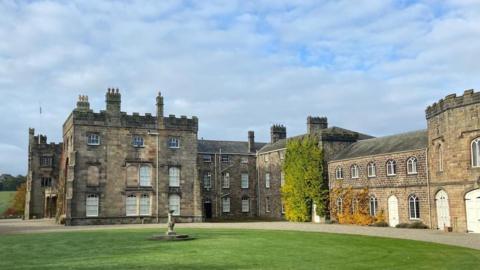 The Ripley Castle estate close up, the open grass area with stone statue is visible in front of the property. 