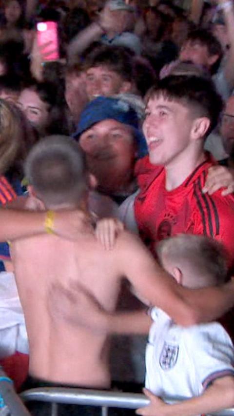 People are hugging and jumping in the air, smiling.