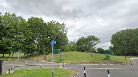 A cycle and foot path in front of a grassy wooded area