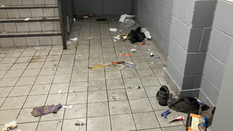 The inside of a building showing a stairwell littered with rubbish.