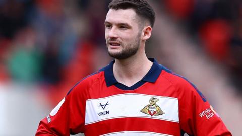 Luke Molyneux in action for Doncaster Rovers in their red and white hooped home jersey