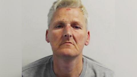 A police mug shot of William Feely, a man with greying hair