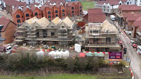 Construction work on part of the Chilmington Green housing development in Ashford, Kent. The picture shows half-built houses with scaffolding on, with completed three-storey buildings behind