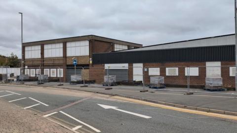 A former factory shop is pictured with metal fencing surrounding it