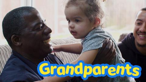 Grandad plays with granddaughter with Dad looking on.