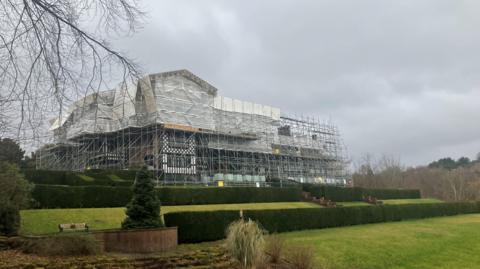 Tudor-era Bramall Hall in Stockport. The image shows some of the parkland and the building surrounded in scaffolding.
