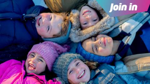 children lying down in a circle laughing with heads together.