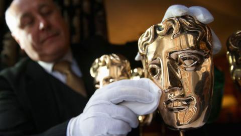 A man polishing a Bafta mask