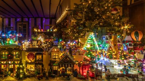 Lots of buildings made from Lego are dotted about. On the right is an ice rink with figures on it, and to the left are houses. 