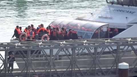 A group of migrants from small boats wearing life jackets and being brought ashore at Dover on 18 October, on the bow of the Border Force vessel Hurricane.