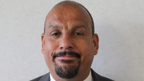 An image of a bald man smiling at the camera