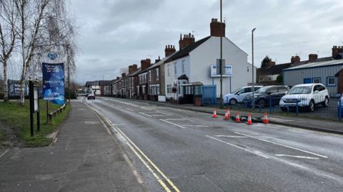 A general view of the A608 Station Road, part of the road is coned off with orange cones.