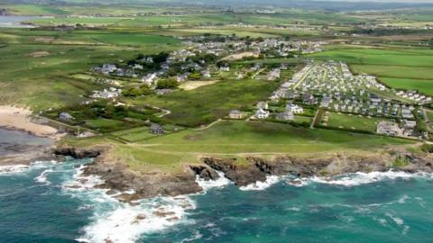 An aerial view of Cornwall showing countryside and the sea, as well as some buildings and agricultural areas