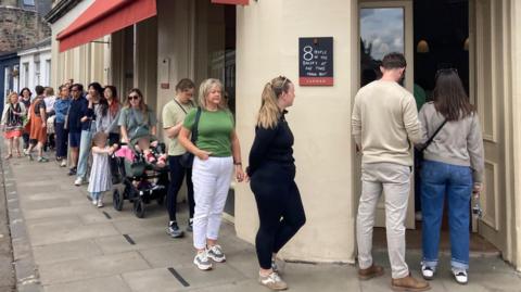 A large queue snakes down the street outside the bakery.