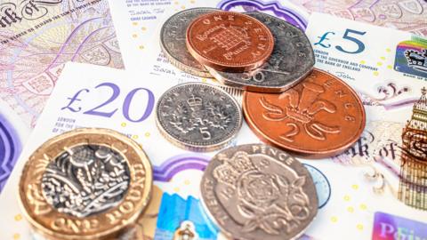A pile of UK banknotes and coins.