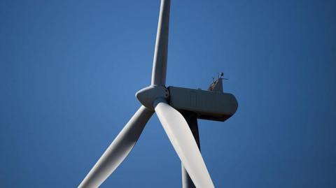 Close up shot of the top section of a white industrial wind turbine.