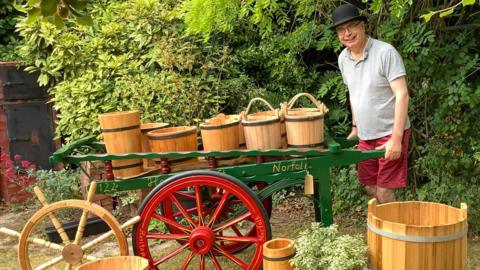 Man with collection of wooden buckets.