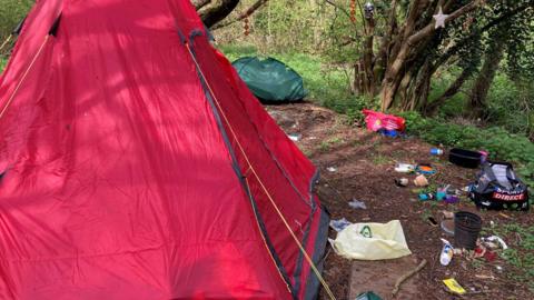 A large red tent, and another smaller green one, as well as lots of rubbish, have appeared in woodlands.
