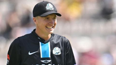 Henry Cullen in his black Worcestershire Rapids kit smiles as his side takes a wicket during a 50-over game