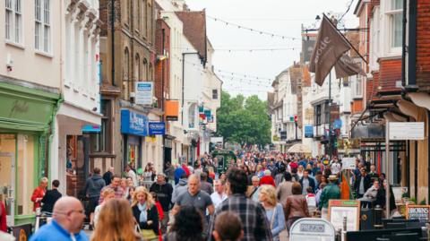 A crowded town high street which is pedestrianised