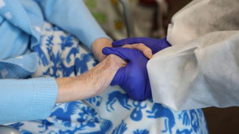 A care home worker holding hands with a resident