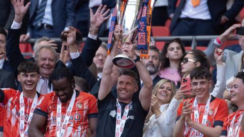 Rob Edwards lifts the play-off winners' trophy 
