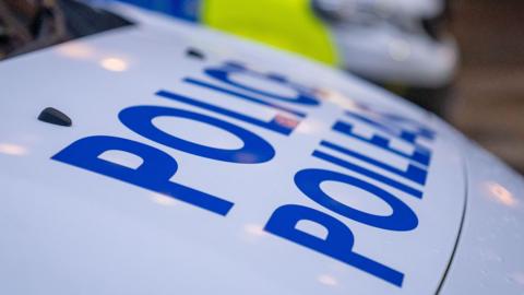 The white bonnet of a vehicle with the world POLICE in blue bold letters on it.